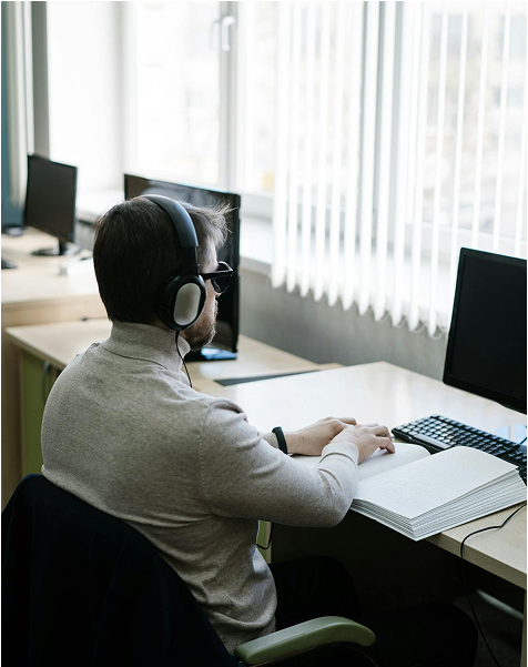 Osoba pracující u počítače se sluchátky